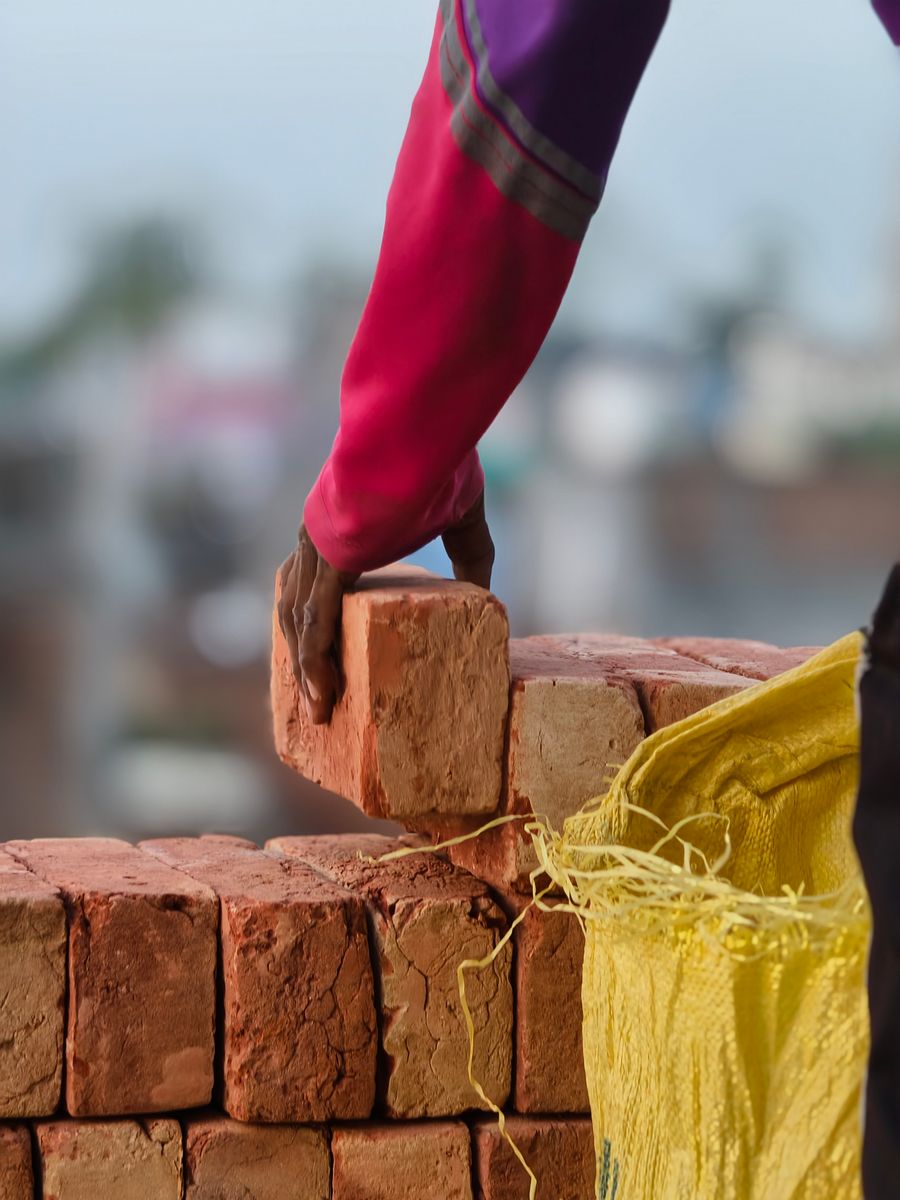 Bricklayer setting a brick in a wall